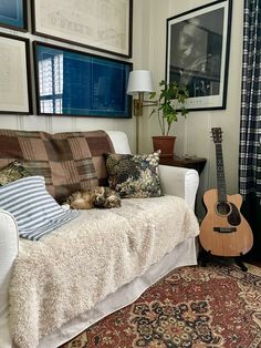 a living room with a couch, guitar and pictures on the wall above it's head