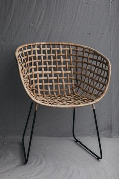 a wicker chair sitting on top of a black metal frame stand next to a gray wall