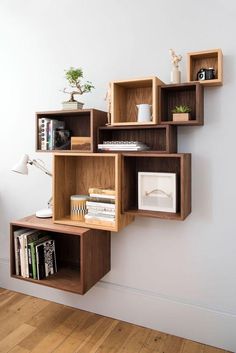 a wooden shelf with books and other items on it in front of a white wall