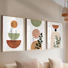 three framed art prints hanging on the wall above a couch in a living room with white walls