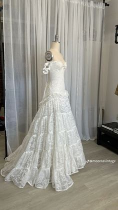 a white wedding dress on display in front of curtains