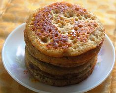 a stack of pancakes sitting on top of a white plate next to a yellow table cloth