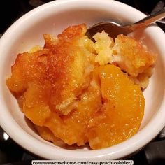 a white bowl filled with peach cobbler and topped with a spoon