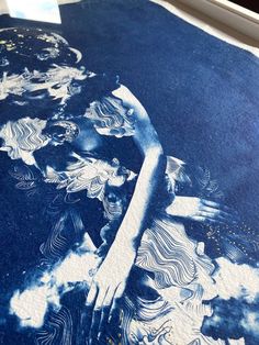 a large blue and white painting on the ground with clouds in it's center