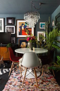 a dining room table with chairs and pictures on the wall above it, next to a rug