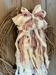 a wreath hanging on the side of a wooden door with ribbon tied around it's edges