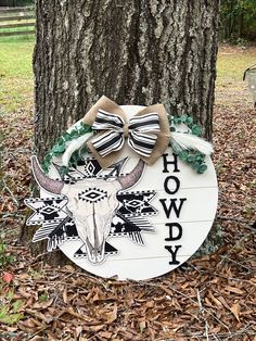 a sign that is next to a tree in the woods with bow decorations on it