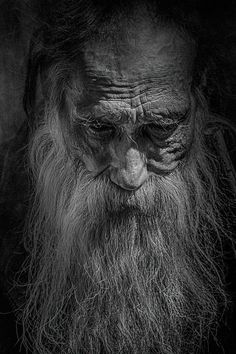 a black and white photo of an old man's face with long beards