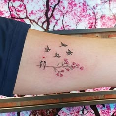 a woman's arm with birds and flowers tattoo on the left side of her arm