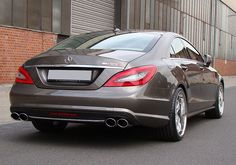 the rear end of a mercedes cla parked in front of a brick building on a city street