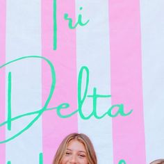 two women standing next to each other in front of a pink and white striped wall