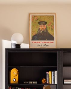 a book shelf with books and an old poster on the wall above it in a living room