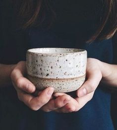 a person holding a white bowl in their hands with dirt all over it and black background