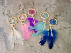 five dream catchers with feathers hanging from them on a stone surface in front of a rock wall