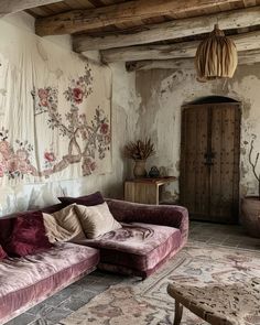 a living room filled with furniture next to a wall covered in floral fabric and hanging curtains