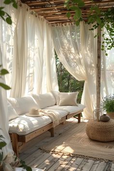 a white couch sitting under a wooden pergol with sheer curtains on it's sides