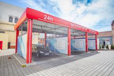 a car is parked in front of a red and white bus stop with the number 24 on it