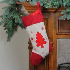 a christmas stocking hanging from a fireplace mantel decorated with pine branches and red stockings