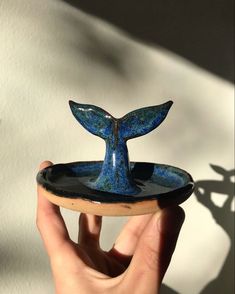 a hand holding a blue whale tail shaped dish