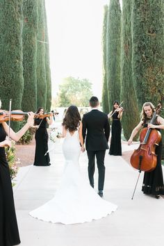 a bride and groom walking down the aisle with their violins in hand as they play music