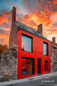 a red brick building with windows on the side and a sky background that is very colorful