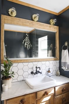 a white sink sitting under a bathroom mirror next to a wooden cabinet and counter top