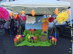 a table with paper flowers and decorations on it at an outdoor market stall in the city