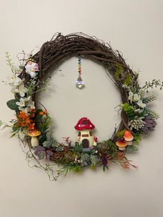 a wreath with a house and flowers hanging on the wall