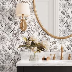 a bathroom with floral wallpaper and marble counter top, gold faucet, white sink and mirror