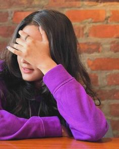 a woman sitting at a table covering her eyes