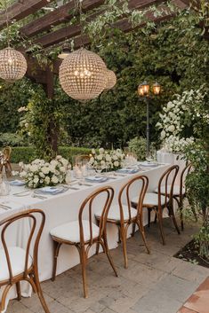 an outdoor dining area with white table cloths and chandeliers