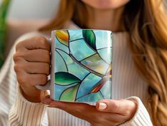 a woman holding a coffee mug with stained glass designs