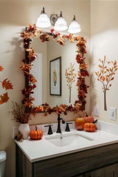 a bathroom decorated for fall with pumpkins and leaves on the mirror above the sink