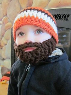 a little boy wearing a crocheted hat and beard with an orange and white stripe