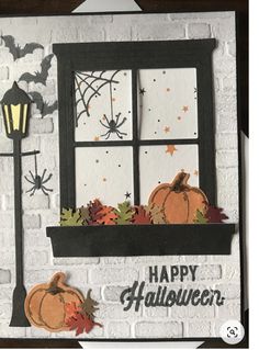 a handmade halloween card with a window and pumpkins on the windowsill, in front of a brick wall