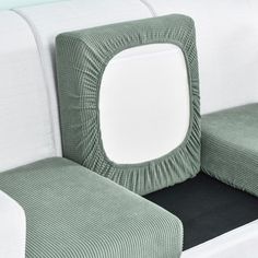 a white and green couch with two square pillows on it's backrests