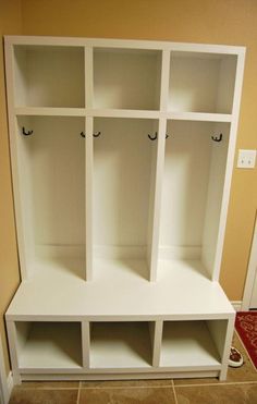 a white bookcase with four cubbys and two doors on each side in a room