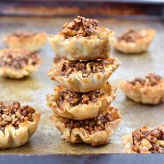 mini pecan pies stacked on top of each other in the middle of a baking sheet