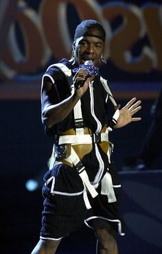 a man standing on top of a stage with his hands in the air while holding a microphone