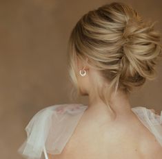 a woman with blonde hair wearing a white wedding dress and earrings, looking off to the side