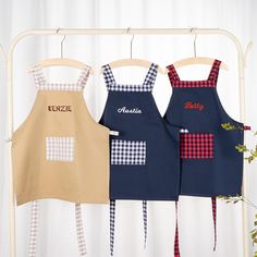 three children's aprons hanging on a rack