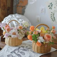 two wicker baskets with flowers in them on a table