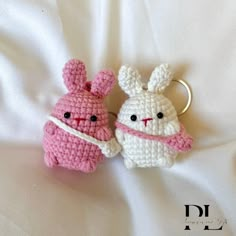 two crocheted stuffed animals sitting on top of a white bed next to each other