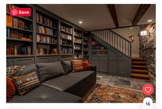 a living room filled with furniture and bookshelves next to a stair case in front of a stone wall