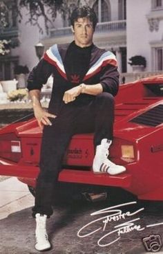 a man sitting on top of a red sports car