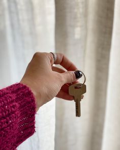 a hand holding a key to a curtain with a ring on it's thumb