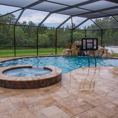 a pool with a hot tub inside of it next to a large stone patio area