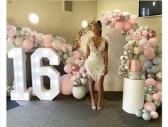 a woman standing in front of a giant balloon arch with the number 16 on it