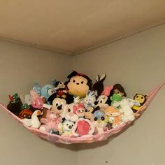 a shelf filled with lots of stuffed animals on top of a white wall next to a window