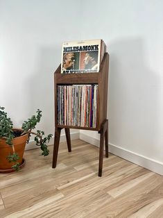 a record player sitting on top of a wooden stand next to a potted plant